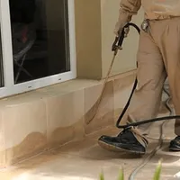 General pest control technician spraying exterior perimeter around a home in Arlington, TX