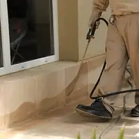 General pest control technician spraying exterior perimeter around a home in Arlington, TX