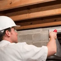 Termite inspection technician checking a basement wall and framing for termite activity in Arlington, TX