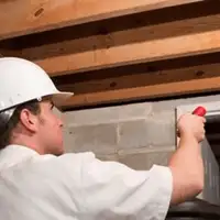 Termite inspection technician checking a basement wall and framing for termite activity in Arlington, TX